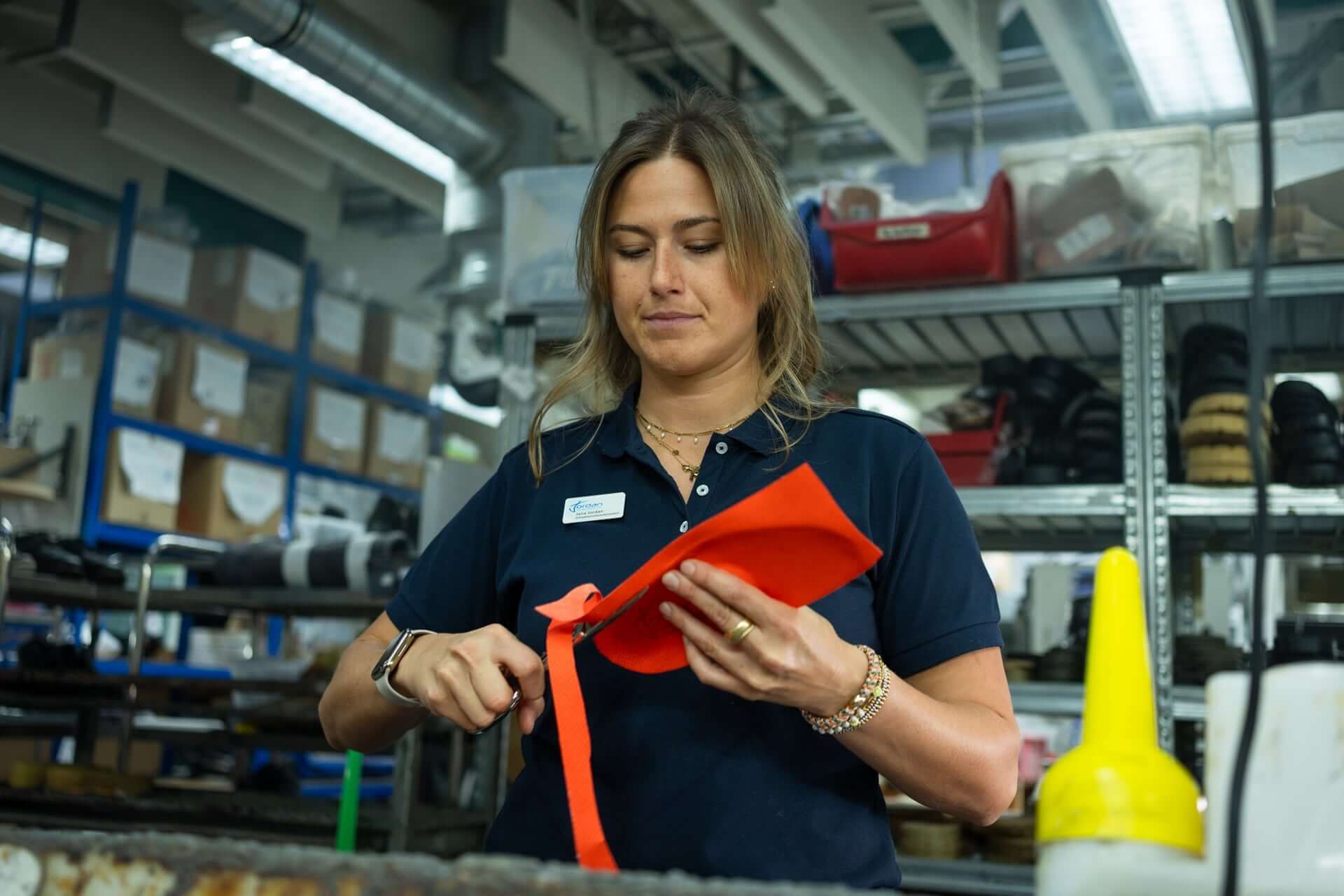 Mitarbeiterin der Jordan Orthopädieschuhtechnik zeigt eine orangefarbene orthopädische Einlage